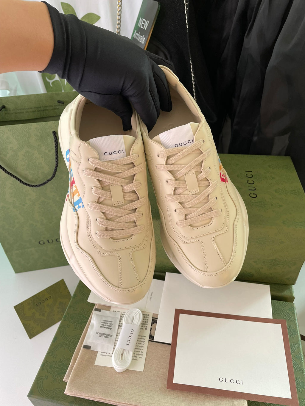 Cream Gucci sneakers shown paired, with lace-up front and brand detailing
