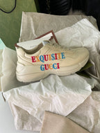 Cream Gucci sneakers with side text “EXQUISITE GUCCI” and thick sole