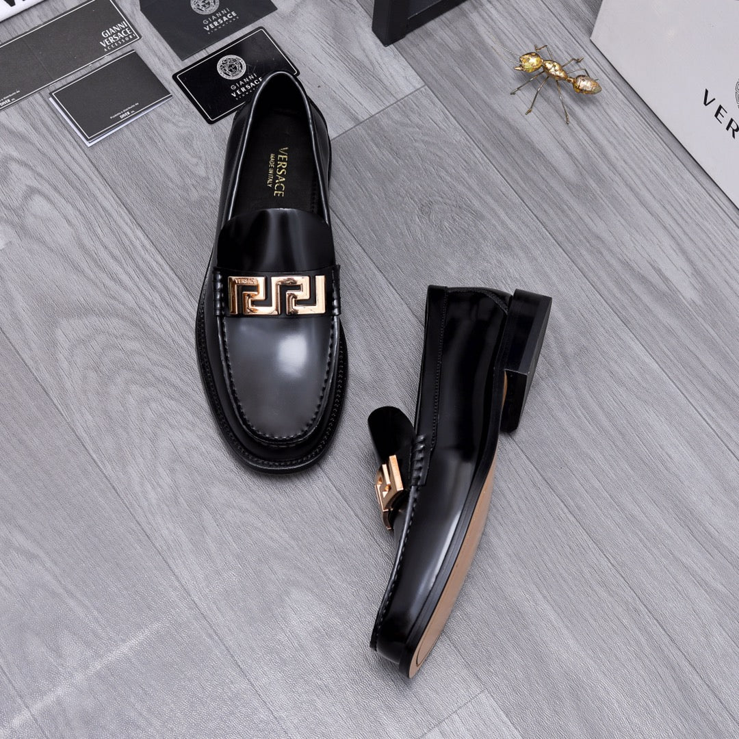 Luxury shoes Versace black leather loafers with gold Greca buckle, laid on floor