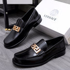 Luxury shoes Versace black leather loafers with gold-tone Greca buckle, angled view