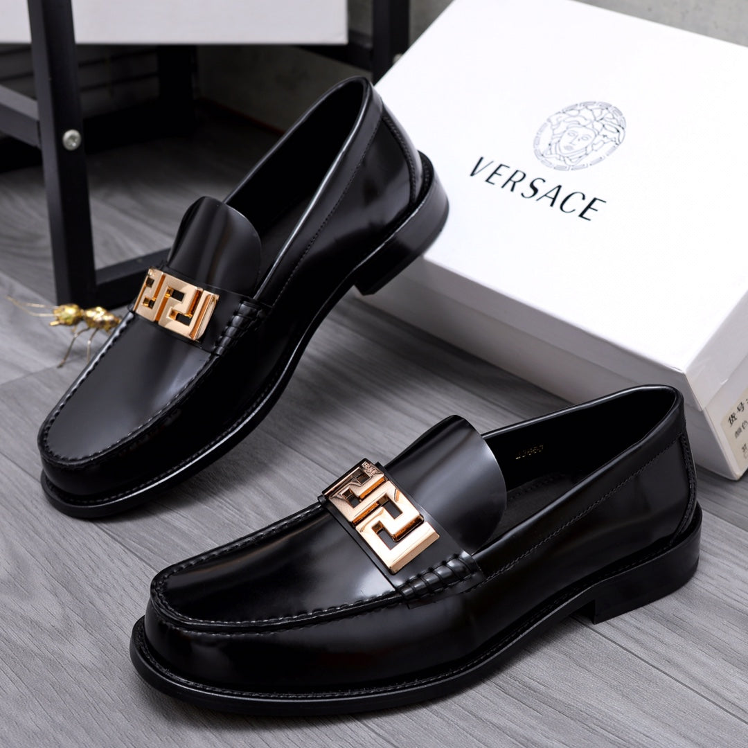 Luxury shoes Versace black leather loafers with gold-tone Greca buckle, angled view