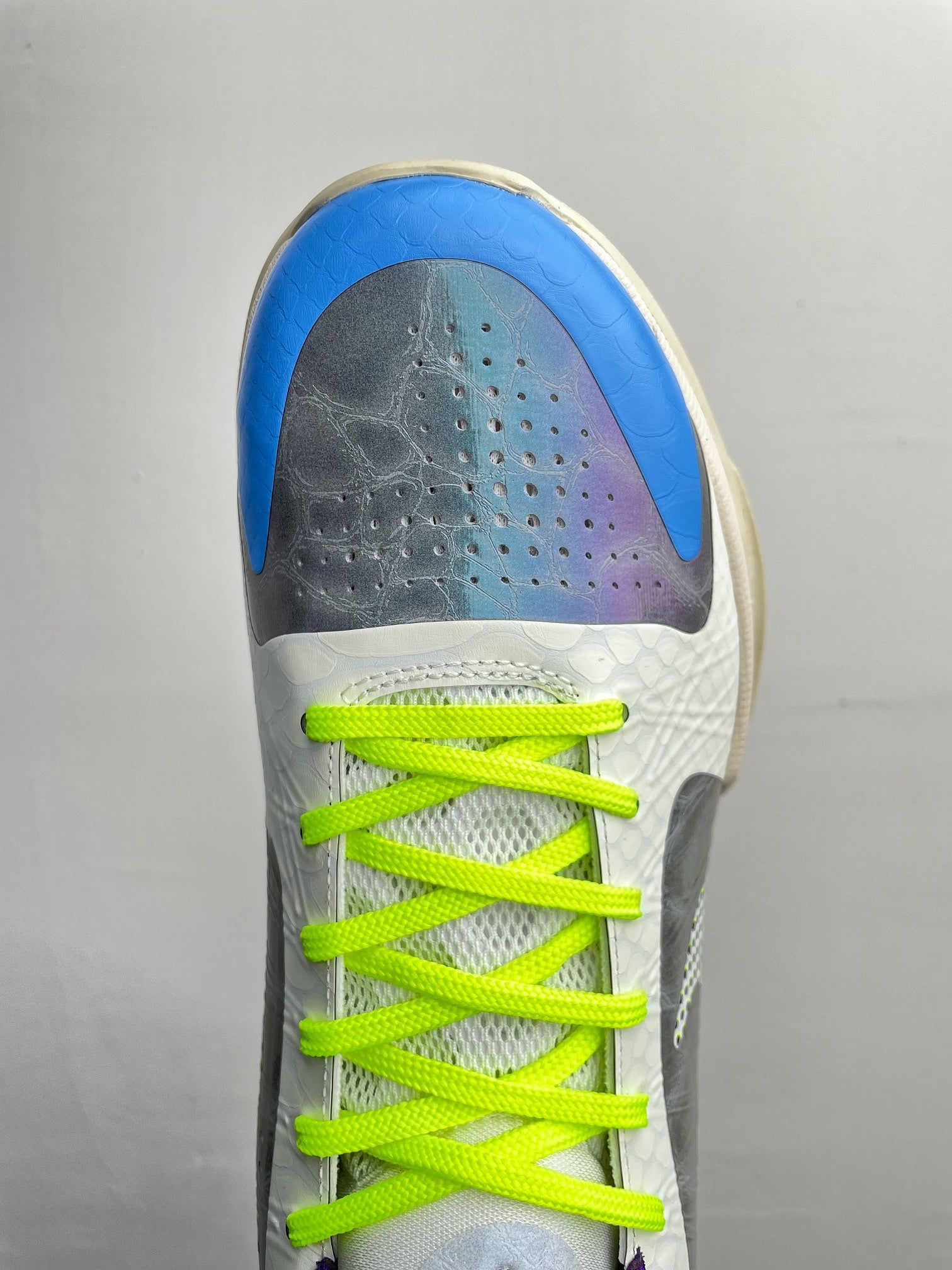 Basketball shoes top view with blue toe, perforations, neon green laces, and white upper