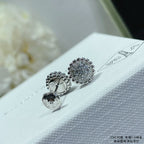 Round pavé stud earrings in silver-toned metal on a white jewelry pouch