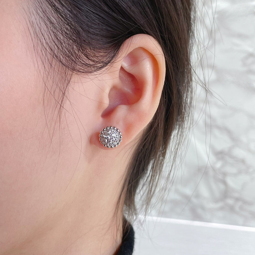Round pavé stud earring in silver-toned metal on a model wearing the earring