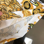 Hand holding Versace patterned shorts fabric in white with gold baroque motifs
