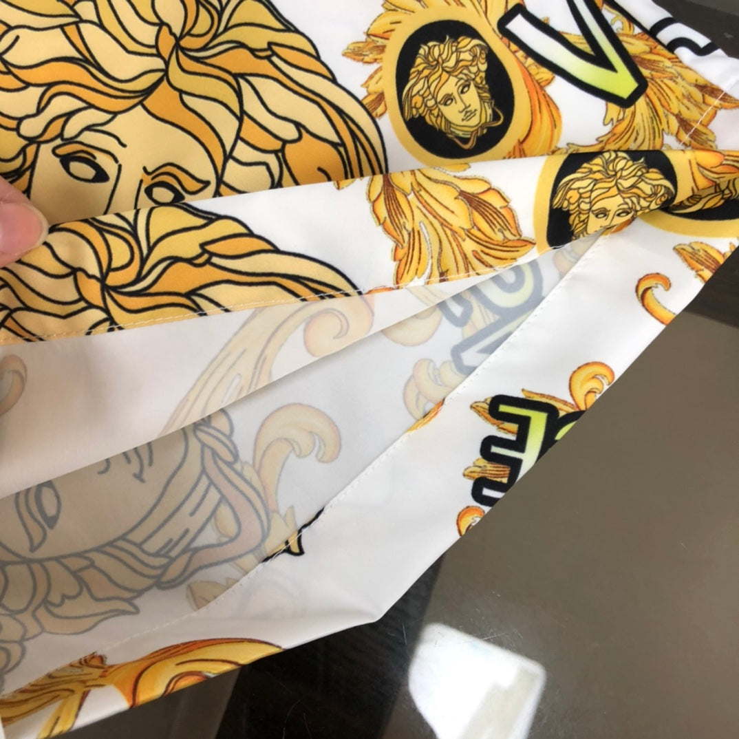 Hand holding Versace patterned shorts fabric in white with gold baroque motifs