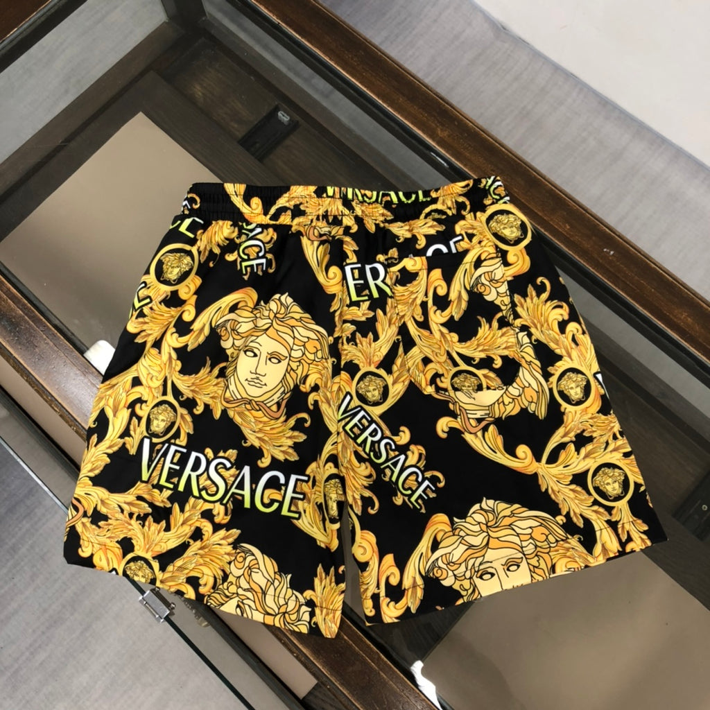 Versace black shorts with gold baroque medusa faces and ERSACE text, elastic waistband
