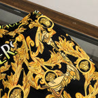Versace black shorts fabric with gold baroque medusa and scroll pattern close-up