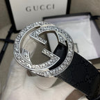 Belt buckle close-up on dark GG canvas strap with silver double-G emblem.