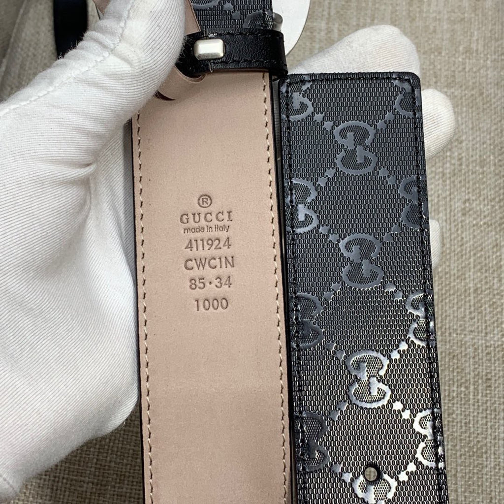 Belt back: tan leather keeper with stamped Gucci details on dark GG canvas.