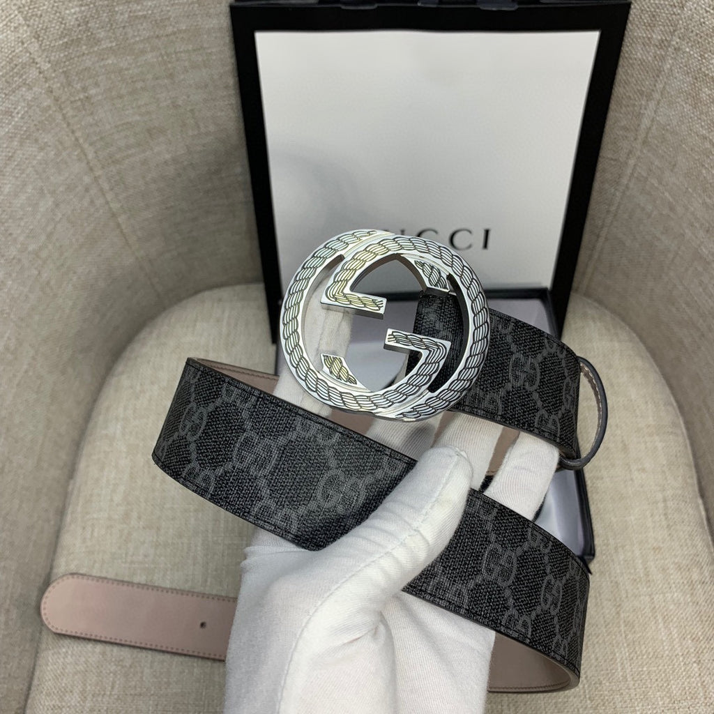 Gucci belt with dark monogram strap and silver G buckle, shown with packaging.