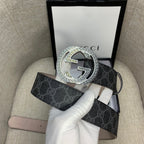 Gucci belt with dark monogram strap and silver G buckle, shown with packaging.