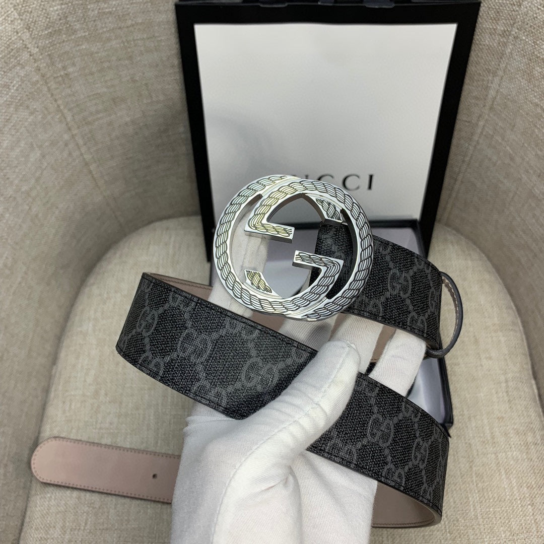 Gucci belt with dark monogram strap and silver G buckle, shown with packaging.