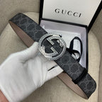 Gucci belt with dark monogram strap and silver G buckle, held in hand.