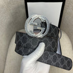 Gucci belt with dark monogram strap and large silver G buckle, angled view.