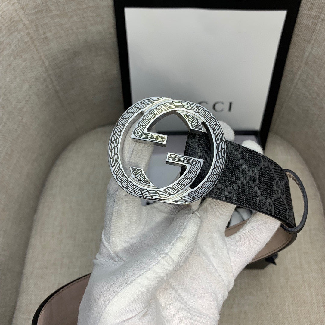 Gucci belt buckle close view on dark monogram strap with silver G emblem.
