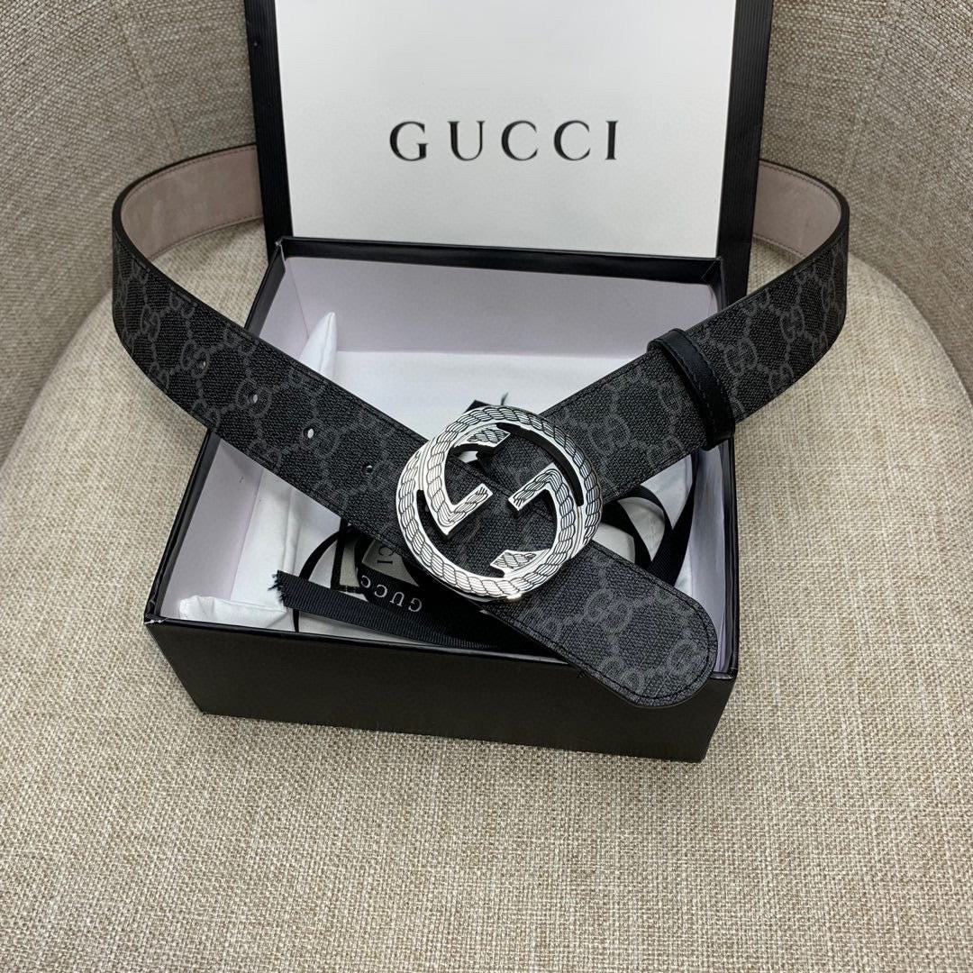 Gucci belt with dark monogram strap and silver G buckle in open box.