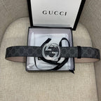 Gucci belt with dark monogram strap and silver G buckle, laid across box.