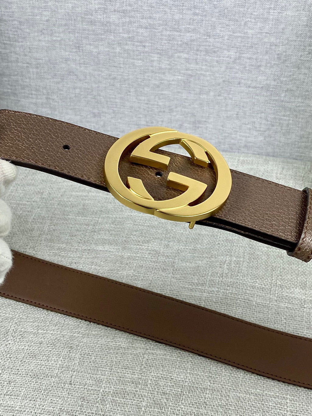 Brown leather belt with gold-tone double G buckle, close-up
