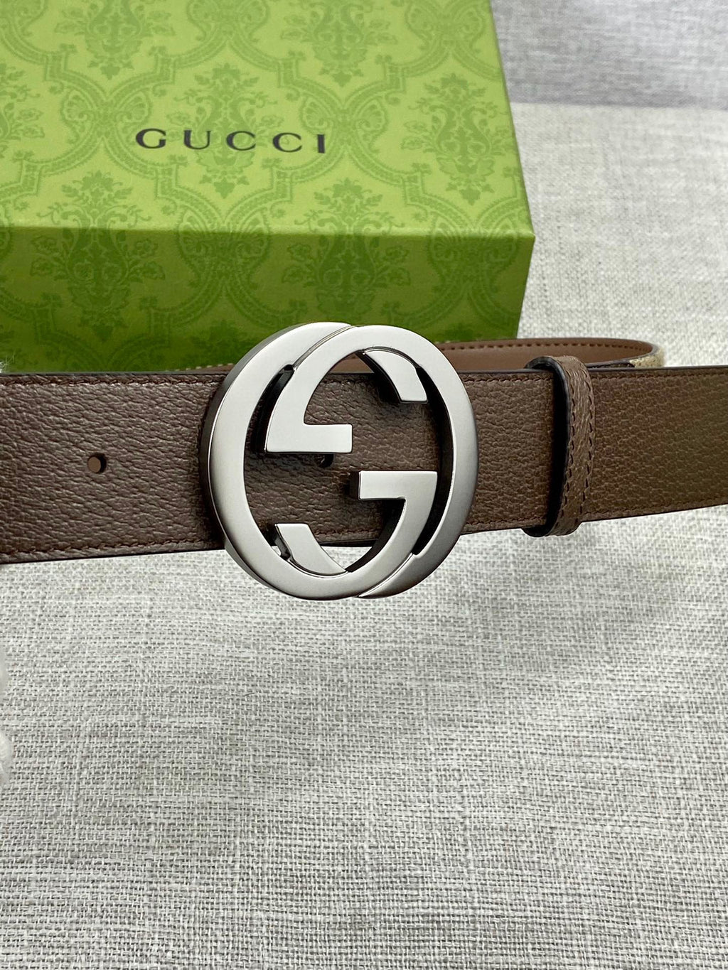 Brown leather belt with large silver round buckle and single leather strap