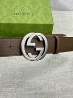 Brown leather belt with large silver round buckle and single leather strap