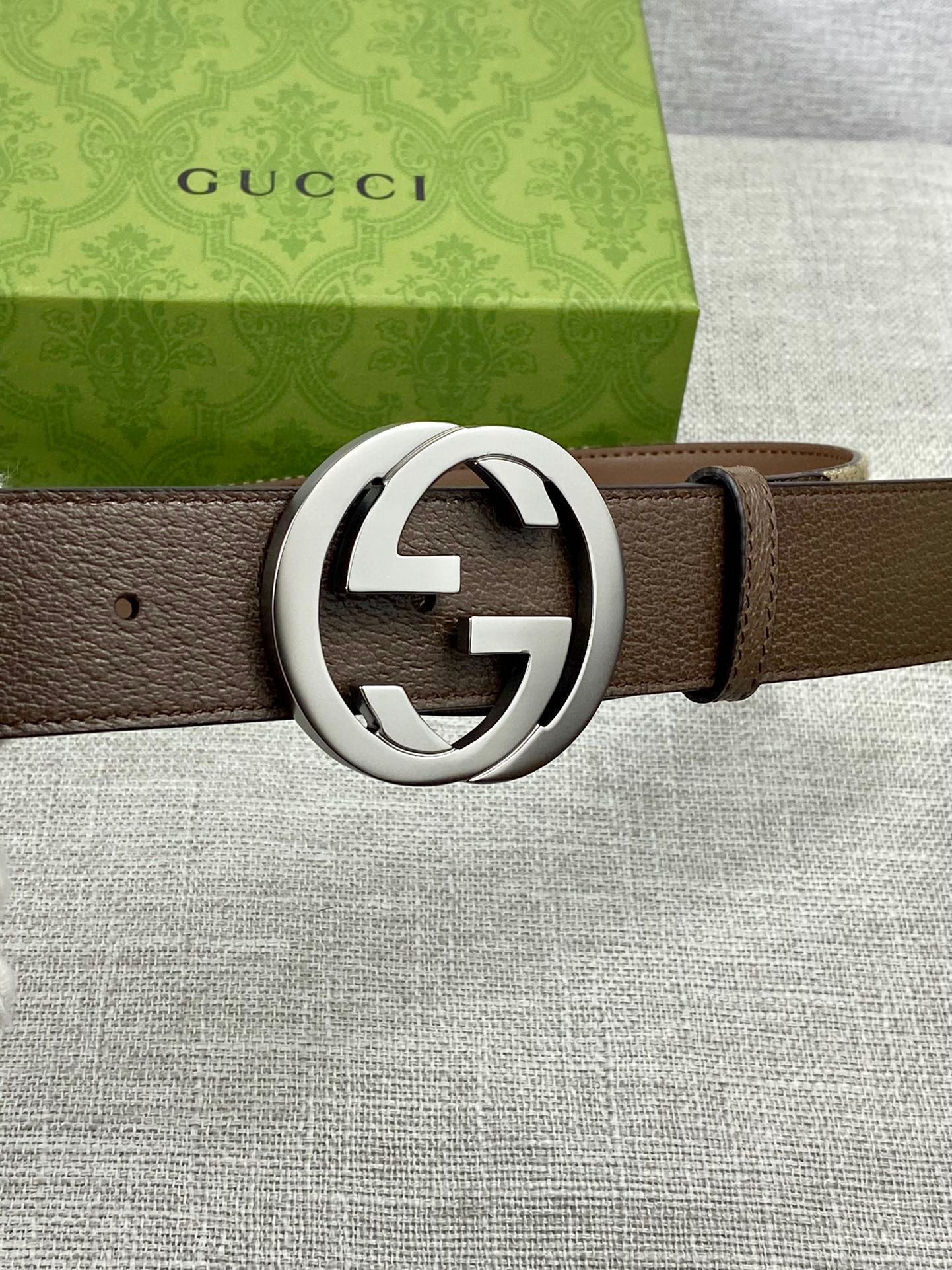 Brown leather belt with large silver round buckle and single leather strap