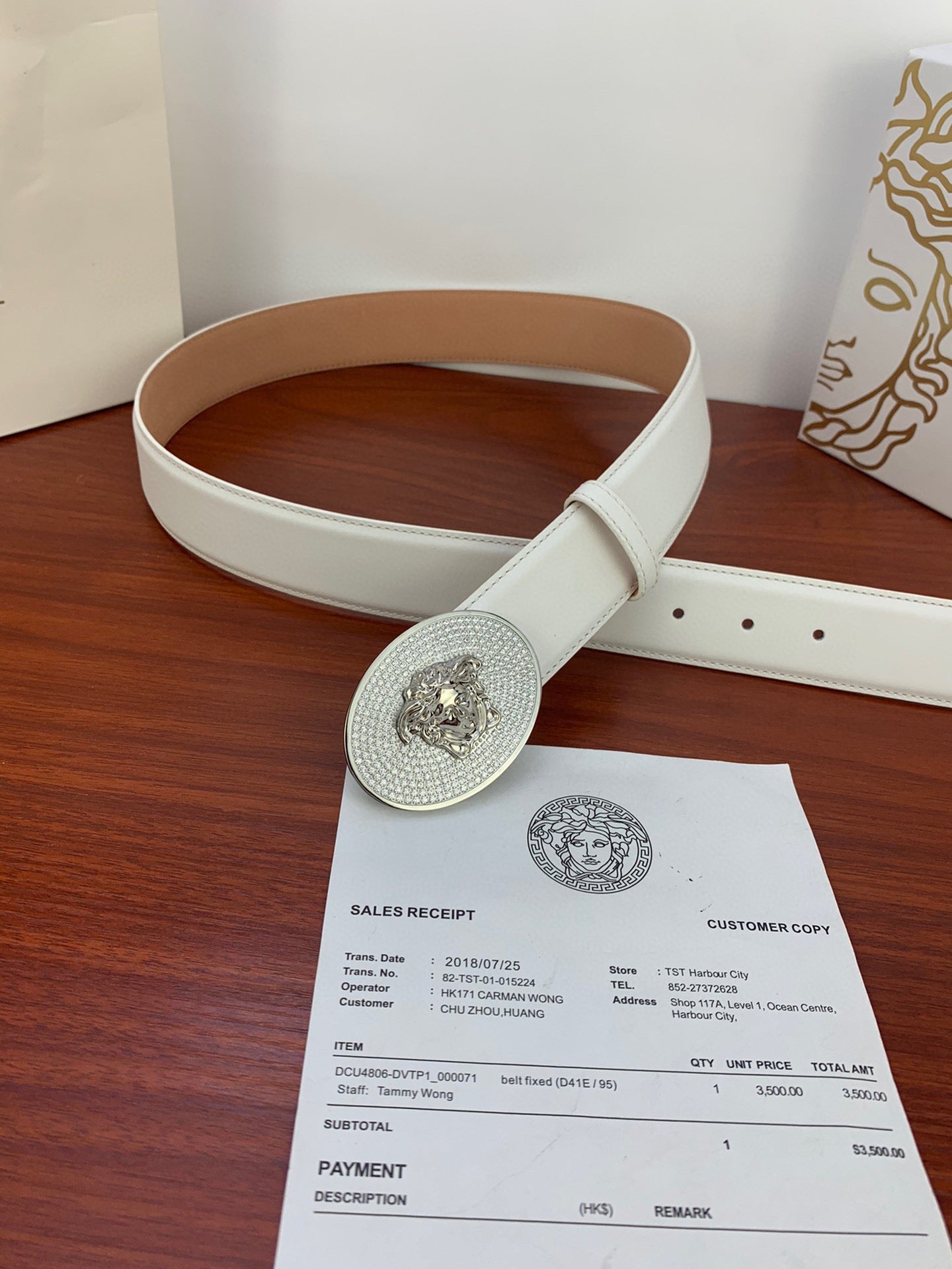 White belt with oval rhinestone buckle laid on table beside receipts