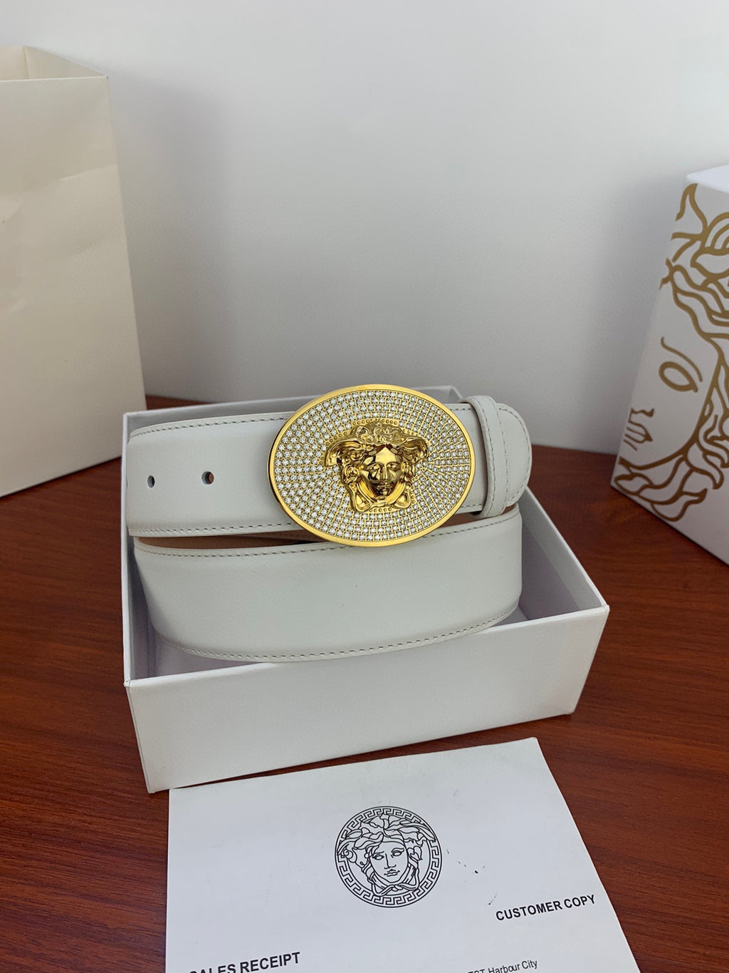 White leather belt with gold rhinestone oval lion buckle in storage box