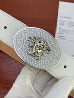 Close-up of oval rhinestone lion buckle on white leather belt
