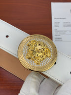 White leather belt close-up with gold Medusa medallion buckle and stitched strap