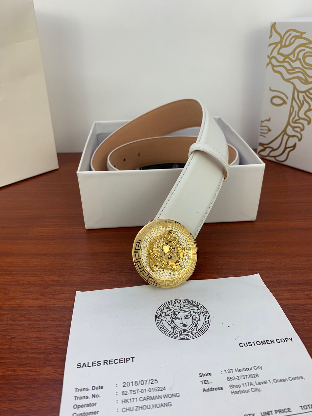 White leather belt with gold Medusa medallion buckle resting in gift box