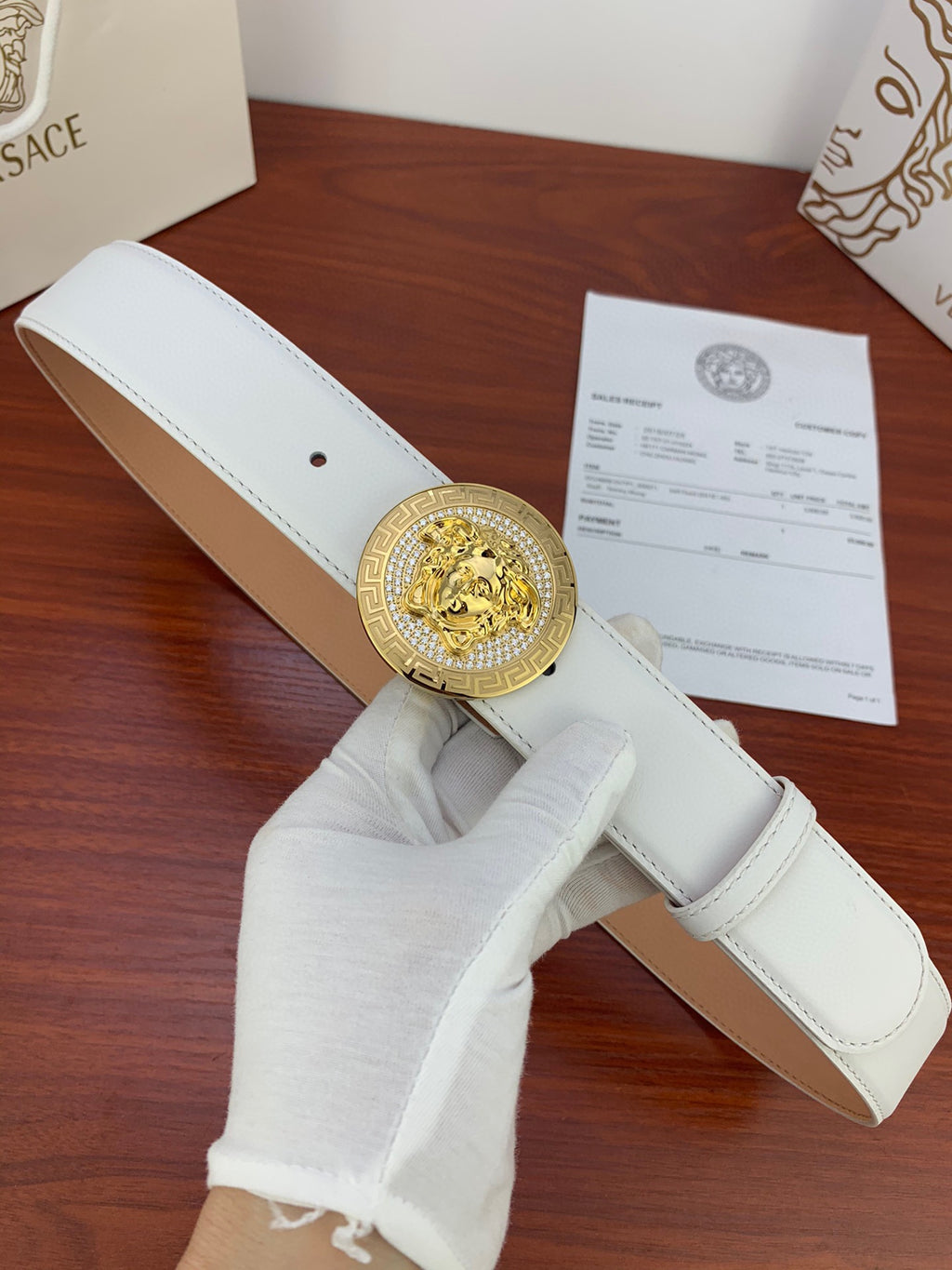 White leather belt with gold Medusa medallion buckle and punched eyelet holes