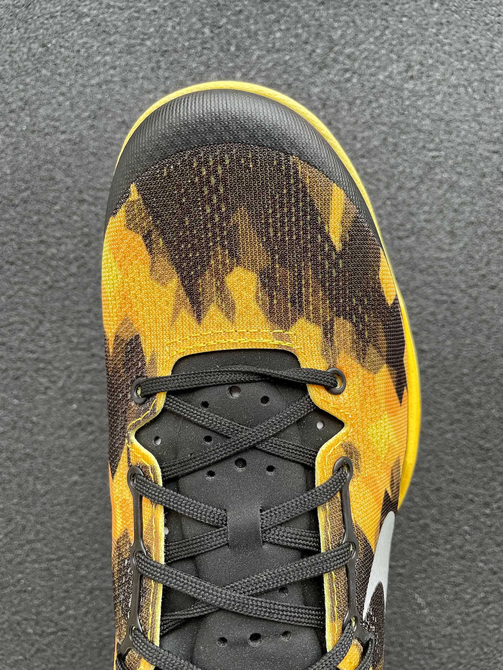 Front view basketball shoe with black laces and black-yellow camo upper