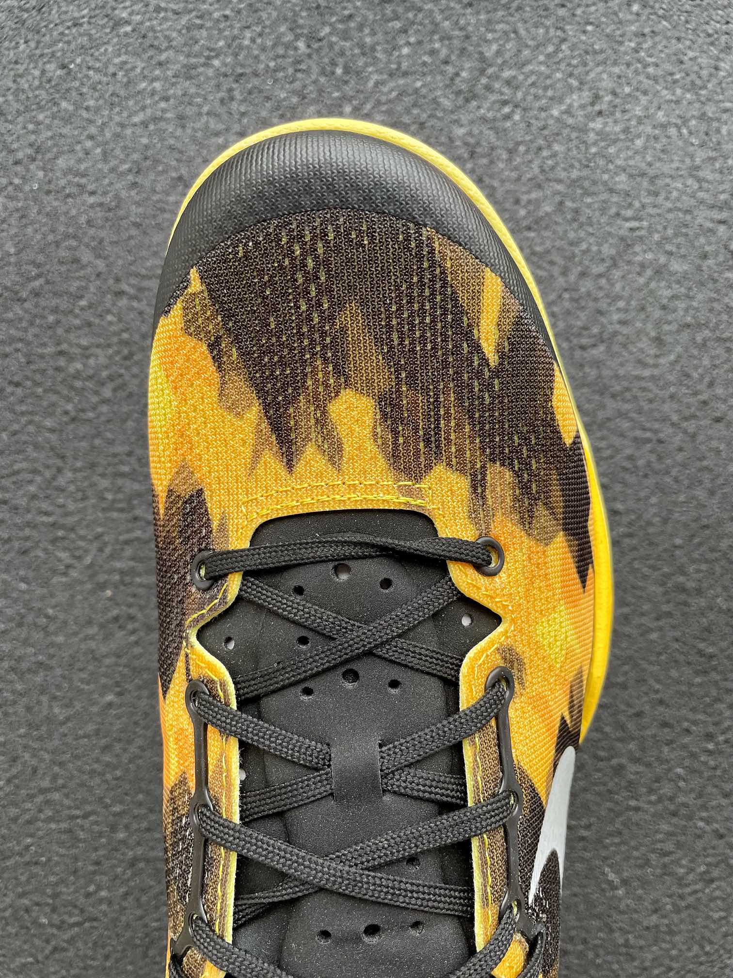 Front view basketball shoe with black laces and black-yellow camo upper