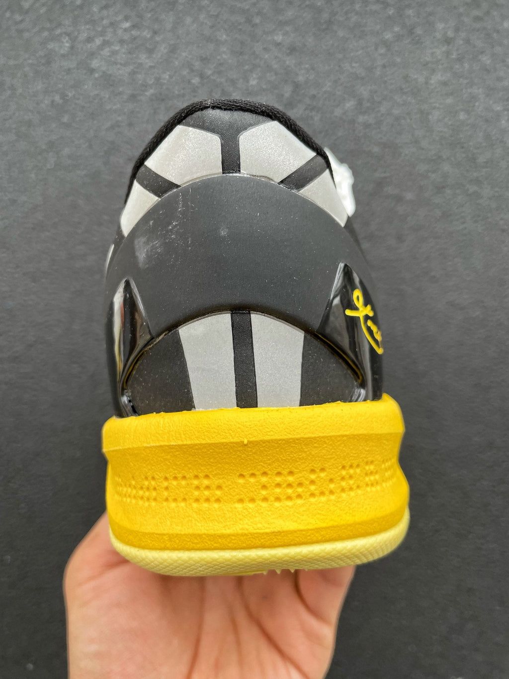 Back view basketball shoe with black heel panel and yellow outsole