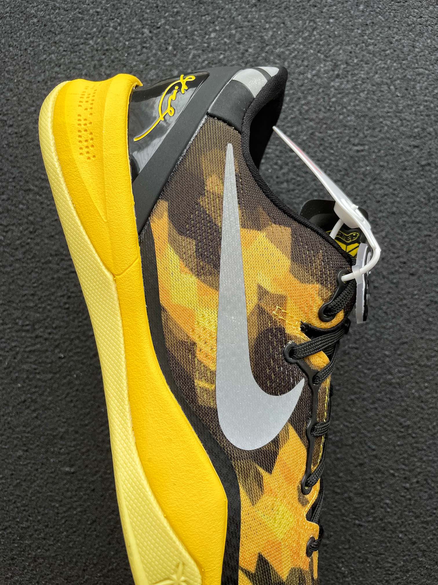 Side view of black and yellow camo basketball shoe with white swoosh
