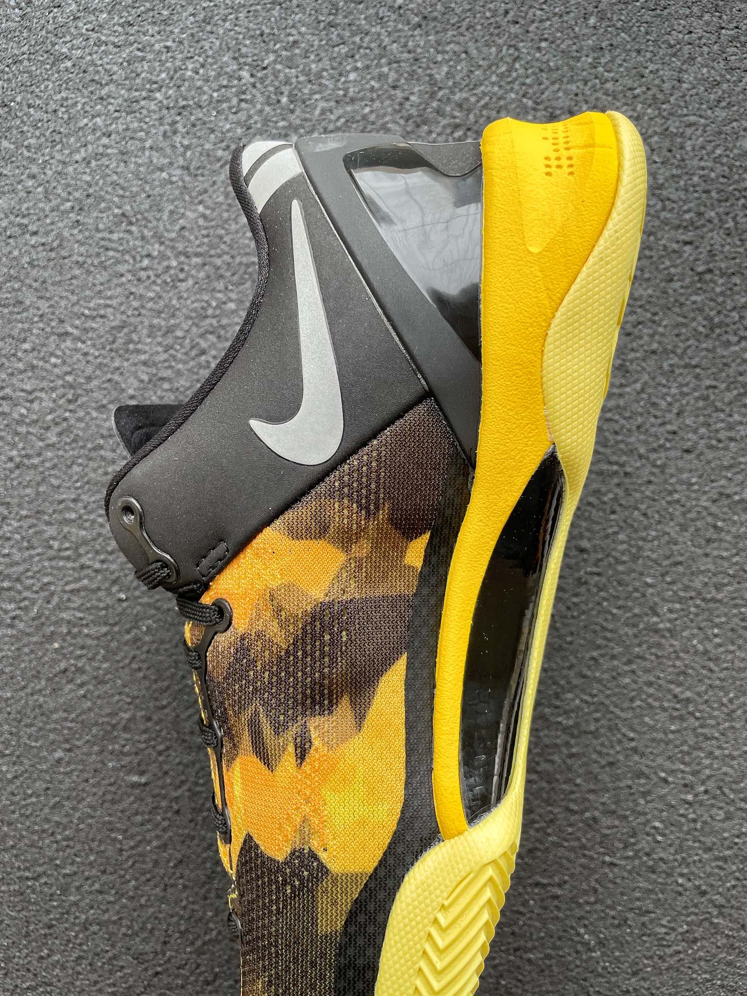 Heel and side of black and yellow camo basketball shoe with swoosh