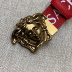 Gold Medusa belt buckle with red Versace logo strap