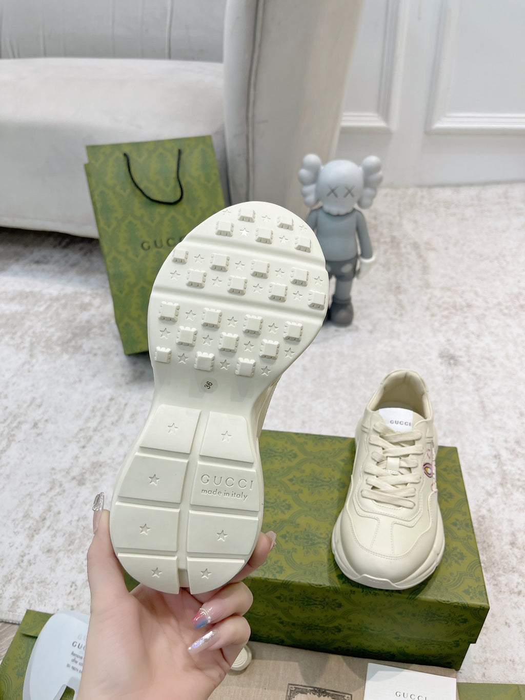 Shoe outsole close-up with studded tread; white lace-up sneaker on green box