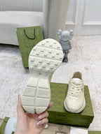 Shoe outsole close-up with studded tread; white lace-up sneaker on green box