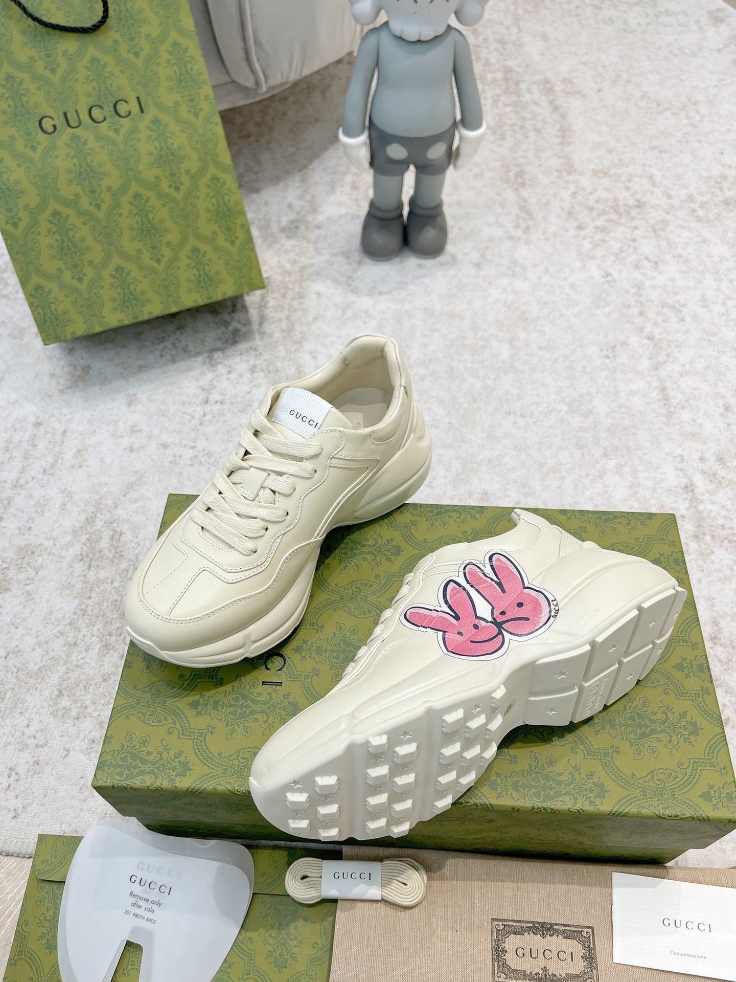 White sneaker with pink-and-blue bunny logo and textured tread sole detail