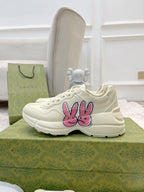 White lace-up sneakers featuring a pink-and-blue bunny graphic on the outer side
