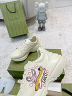 White Gucci lace-up sneakers with colorful cartoon patch on side, close side view