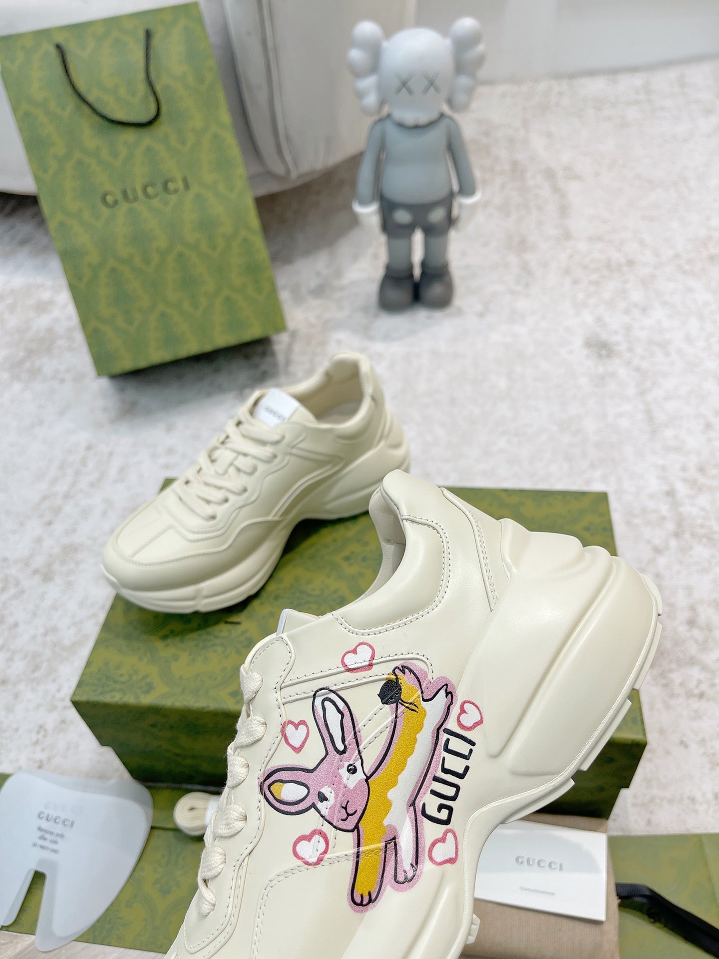 White Gucci lace-up sneakers with colorful cartoon patch on side, close side view