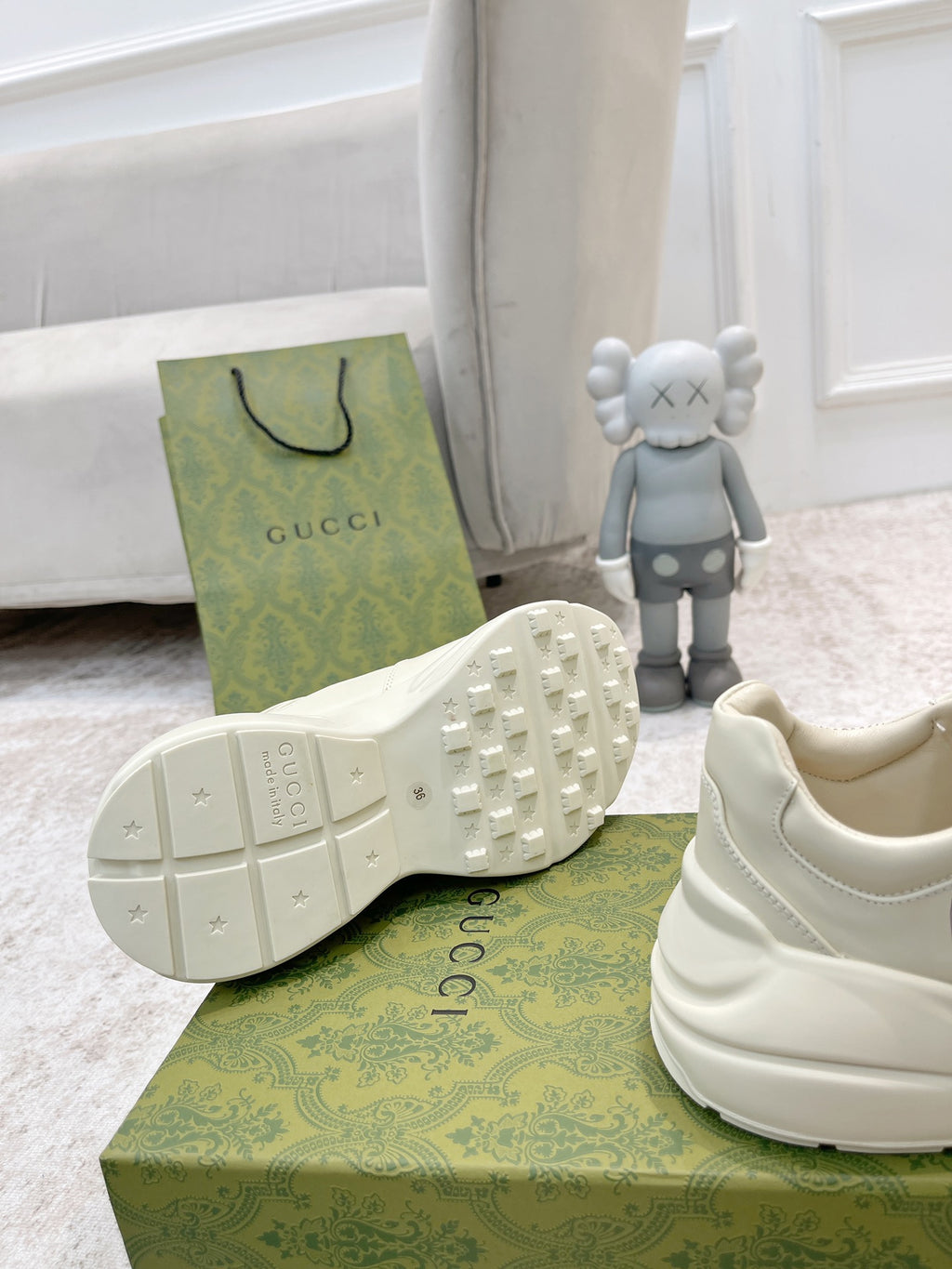 White Gucci sneakers showing tread outsole and side panel, heel and box in view