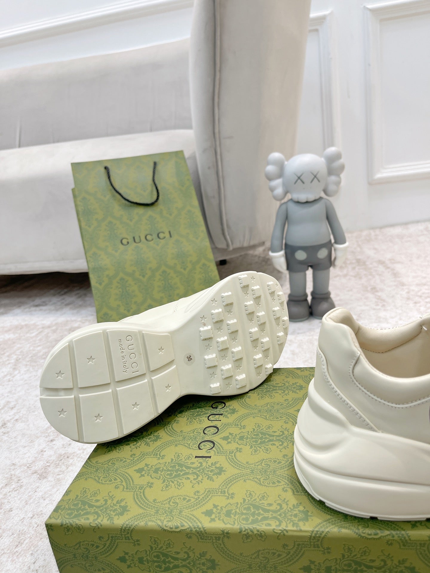 White Gucci sneakers showing tread outsole and side panel, heel and box in view