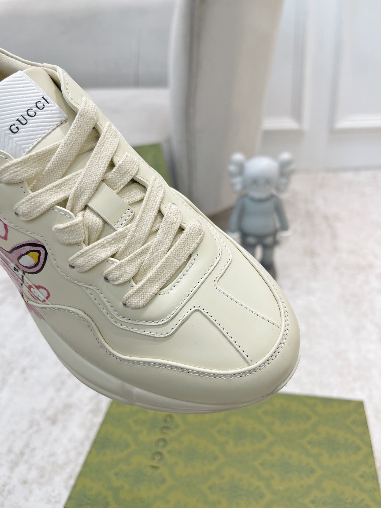 Close-up of white Gucci lace-up sneaker, stitching and side logo graphic details