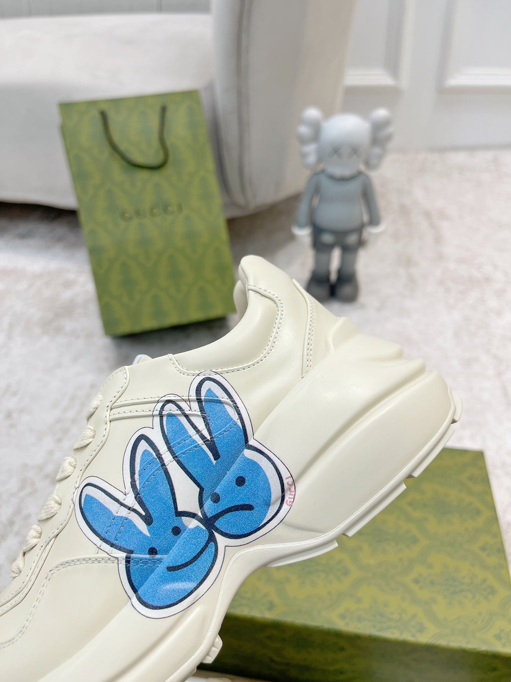 White sneaker with large blue bunny graphic on side, stitched lace-up