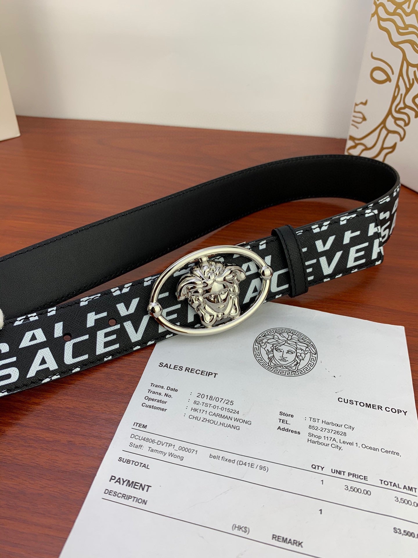 Black Versace belt with repeating white logo and silver Medusa buckle, side angle