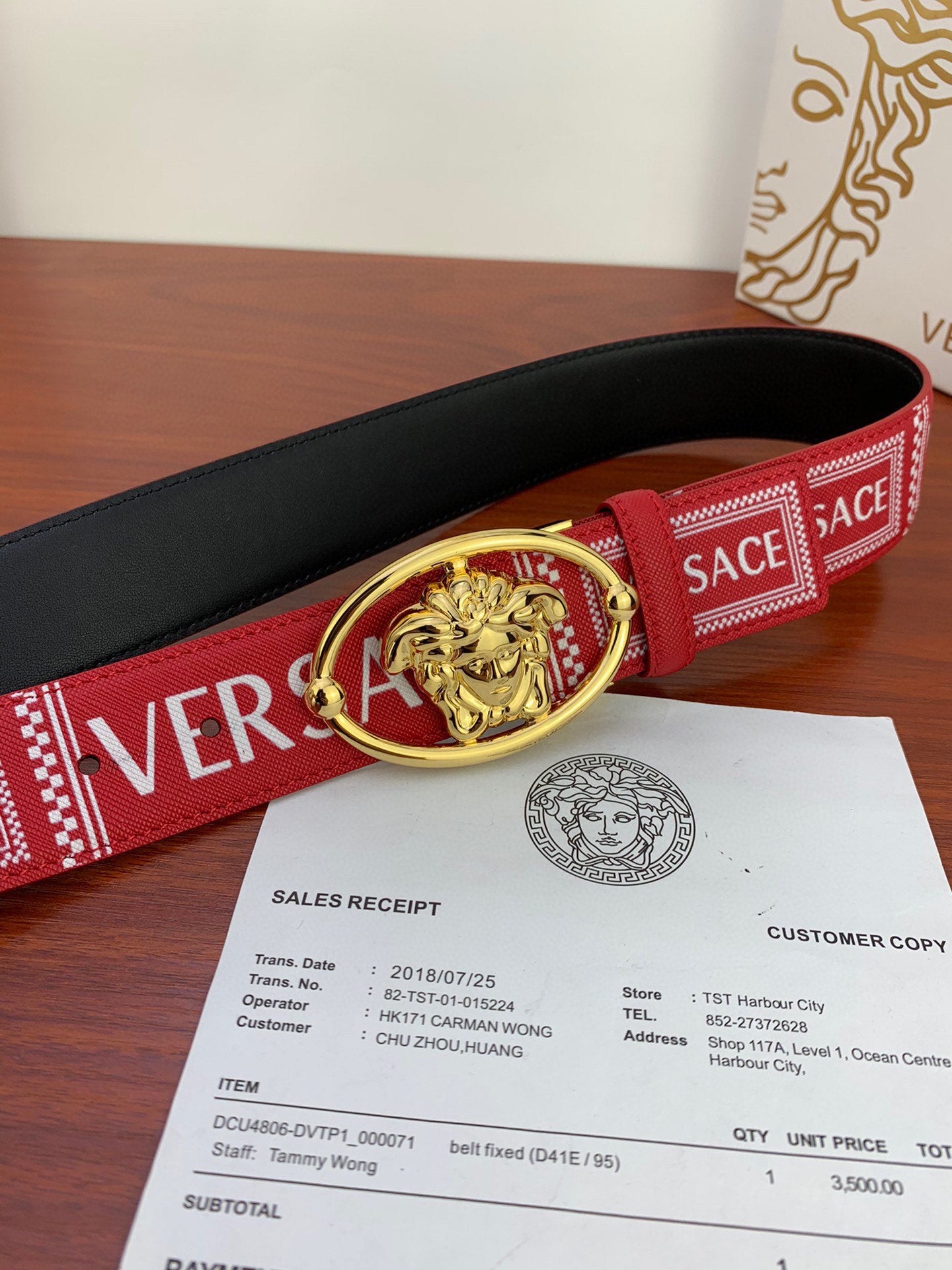 Versace belt with red and black construction, gold Medusa oval buckle, and logo webbing.